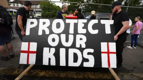 PA Media Two men holding a big placard that reads "Protect our kids".