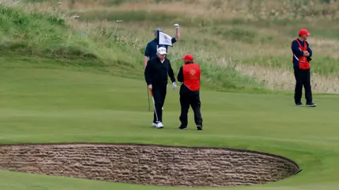 Reuters Two golfers and two caddies on a green