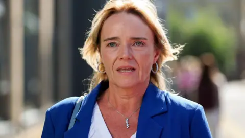 Getty Images A woman with blonde hair in a blue jacket and white shirt. 