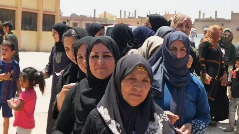 Displaced bedouin women wait for aid