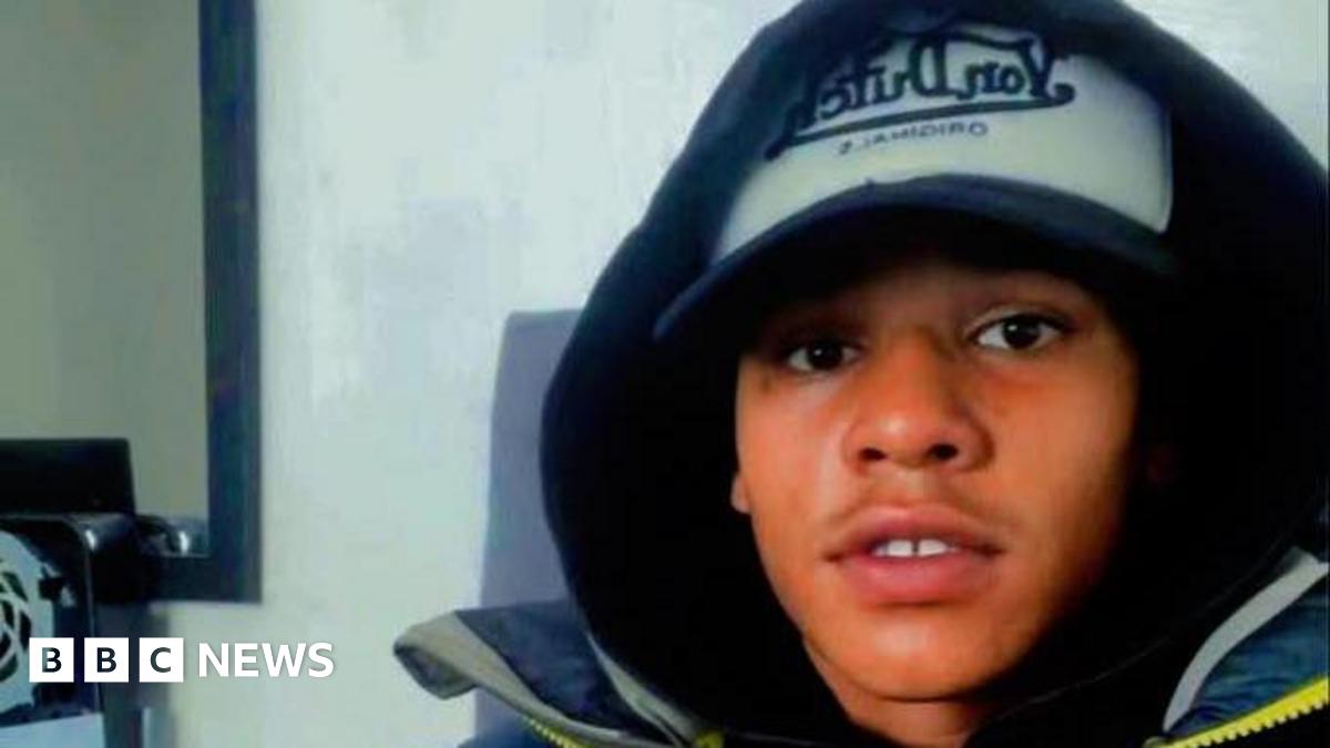 Devon Simmonds is wearing a baseball cap with his hood up. He is staring directly at the camera.