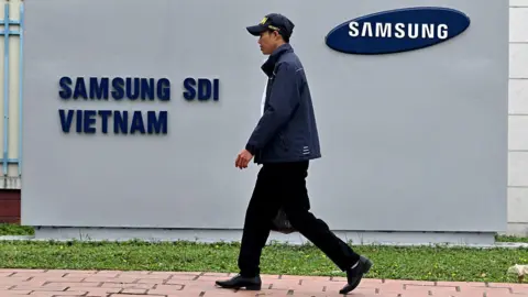 Getty Images This photo taken on April 8, 2025 shows a man in a cap walking past the logo of Samsung Electronics on a billboard in Vietnam's Bac Ninh province.