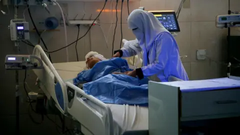 Reuters A Palestinian medic cares for injured people receiving treatment at Nasser hospital, Khan Younis, southern Gaza (9 July 2025)