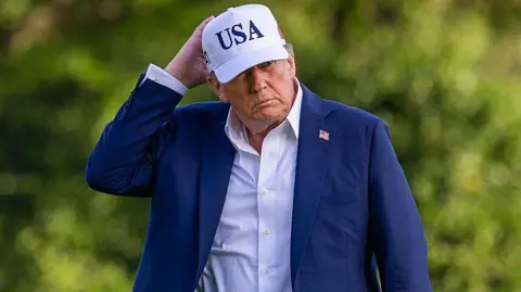 Getty Images US President Donald Trump wearing a blue suit and a white cap with USA on it