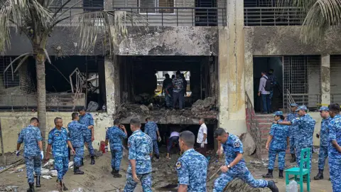 Getty Images Bangladesh Air Force personnel inspect the crash site a day after a training jet crashed into a school in Dhaka on July 22, 2025