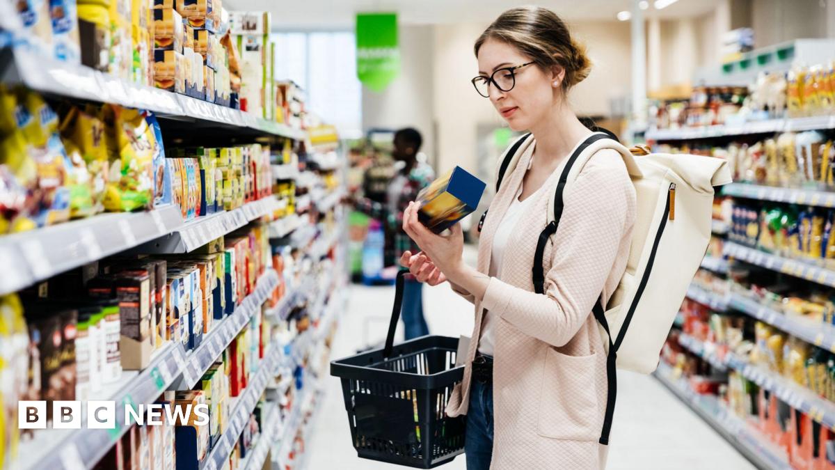 Woman looks at packet of biscuits in supermarket