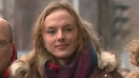 Dr Beth Upton in winter coat and scarf walking along a street.