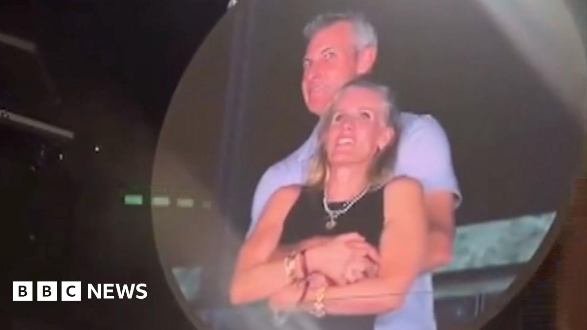 A man and a woman embrace on a big screen