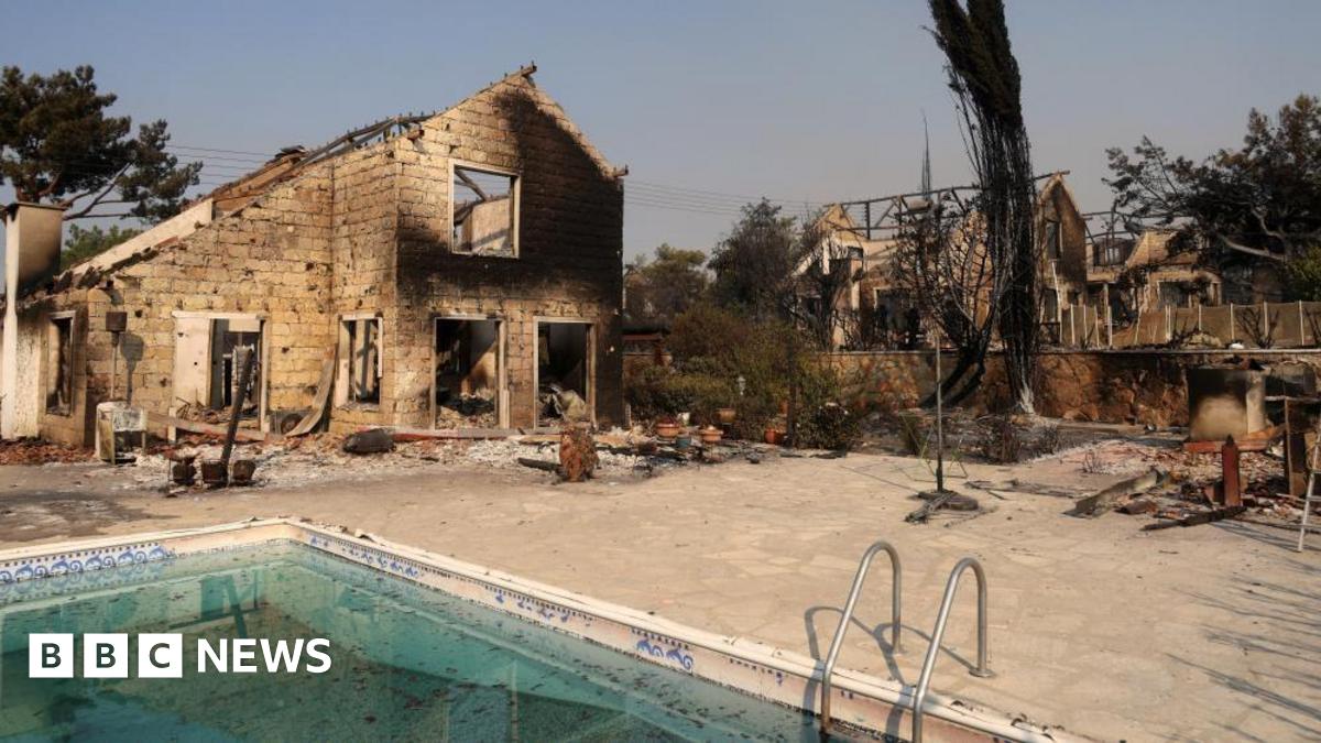 A burned house, which is missing its windows and roof, is seen surrounded by piles of debris