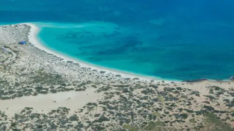 Getty Images An arid coastline seen from the air, with turquoise sea waters and dark patches of reef