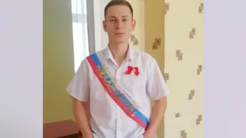 Alexander Petlinsky/VK A picture of a young Russian man in a short-sleeved white shirt with a Russian strap over his shoulder
