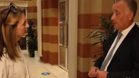 BBC Newsnight Epping Forest District Council leader, Chris Whitbread stands in council building corridor with the BBC's Victoria Derbyshire