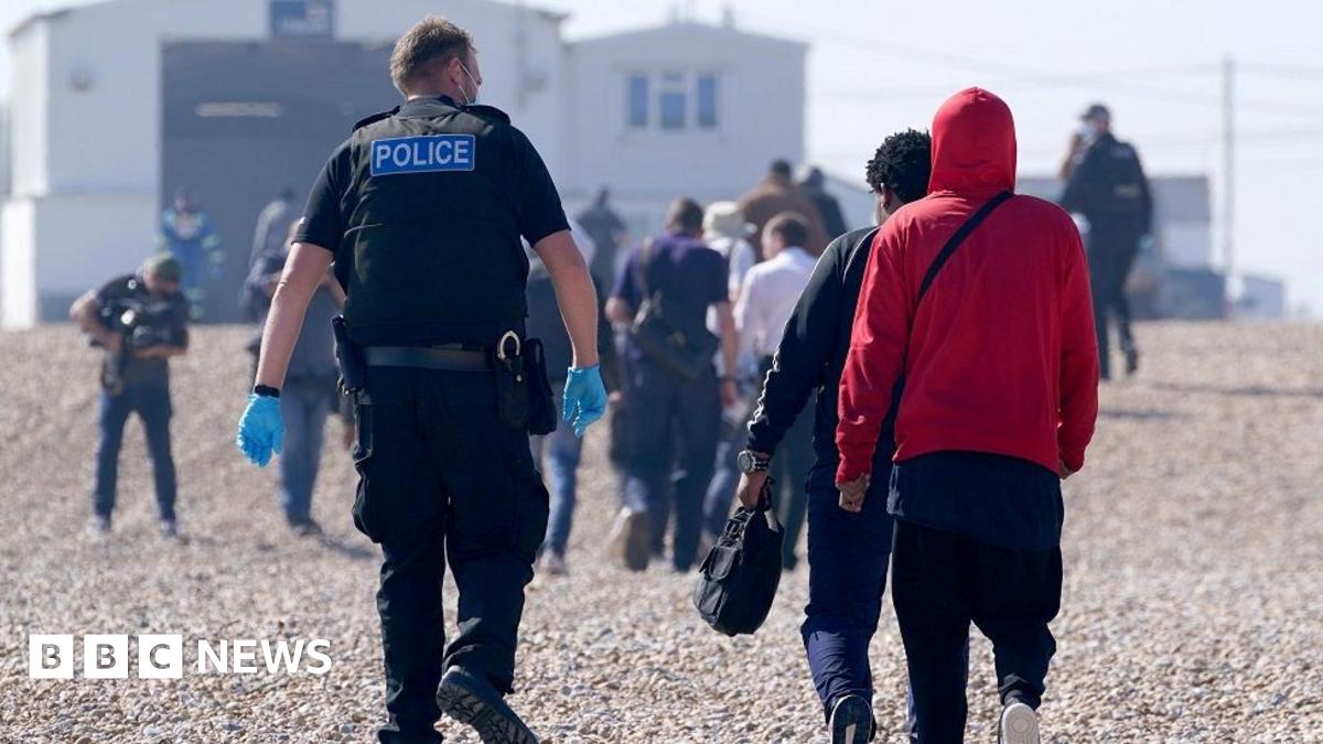 A police officer escorts a group of people thought to be migrants ashore from the Dungeness lifeboat in Dungeness, Kent, after being picked-up following a small boat incident in the Channel