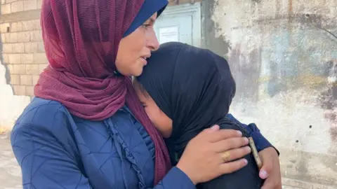 Mary Sheikh al-Eid's daughter, Warshazat (R), is comforted after her body is brought to Nasser Hospital in Khan Younis, southern Gaza (24 July 2025) 