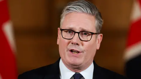 PA Media Sir Keir Starmer giving a statement with two Union Jacks in the background.