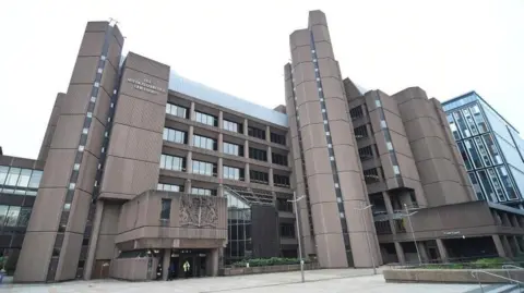 PA Media A large brown block building with a sign on it which reads The Queens Elizabeth II Law Courts
