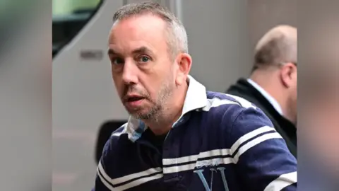 Wales News Service A man with a blue and white striped top, with short greying hair and a grey beard.