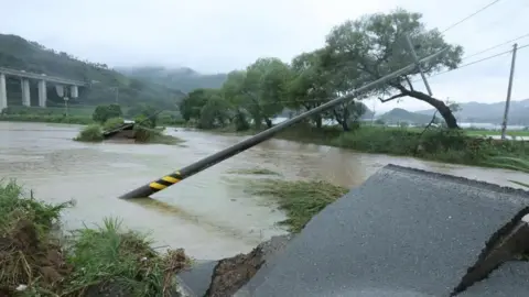 Reuters An electric pole leans over on a damaged road in Gongju, South Chungcheong Province, central South Korea, on 17 July