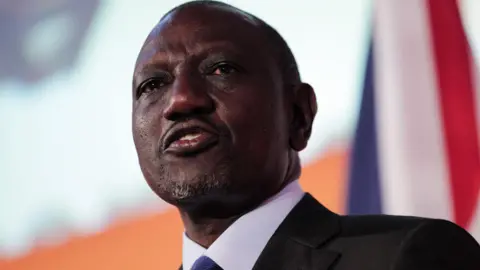 Bloomberg via Getty Images William Ruto, in a black suit, white shirt and blue tie