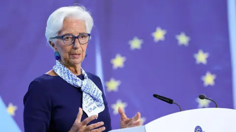 DANIEL ROLAND/AFP Dressed in a dark blue top and a lighter-coloured scarf, Christine Lagarde addresses a press conference with the EU flag behind her