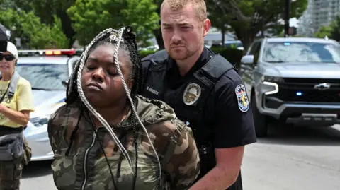 Reuters A police officer holds a woman's hands behind her back as he arrests her on the street