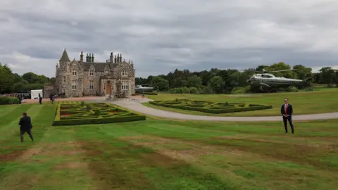 Reuters Two helicopters land around a small castle building in the middle fo a golf course