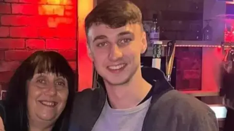 Family handout Jay Slater poses with his arm around his mother Debbie Duncan's shoulder. Both are smiling for the camera.