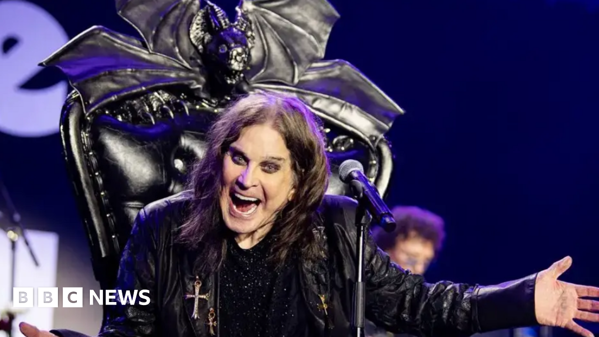 Ozzy Osbourne, dressed in a black leather jacked sat on a black throne with a microphone in front of him