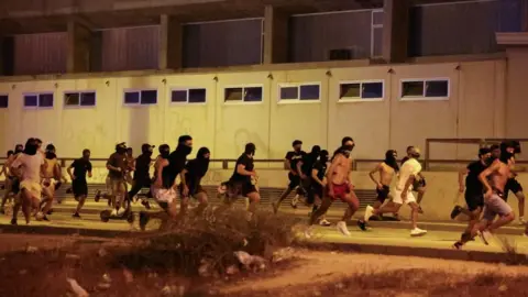 Reuters About two dozen men, many with face coverings, are seen running along a pavement at night in Torre Pacheco