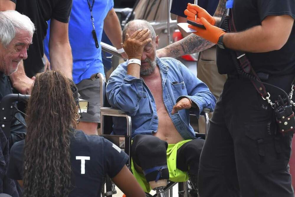 Michael Pimentel, a resident at the Gabriel House assisted living facility, in Fall River, receives assistance from an emergency medical worker outside a temporary shelter on Monday. (Steven Senne/AP)