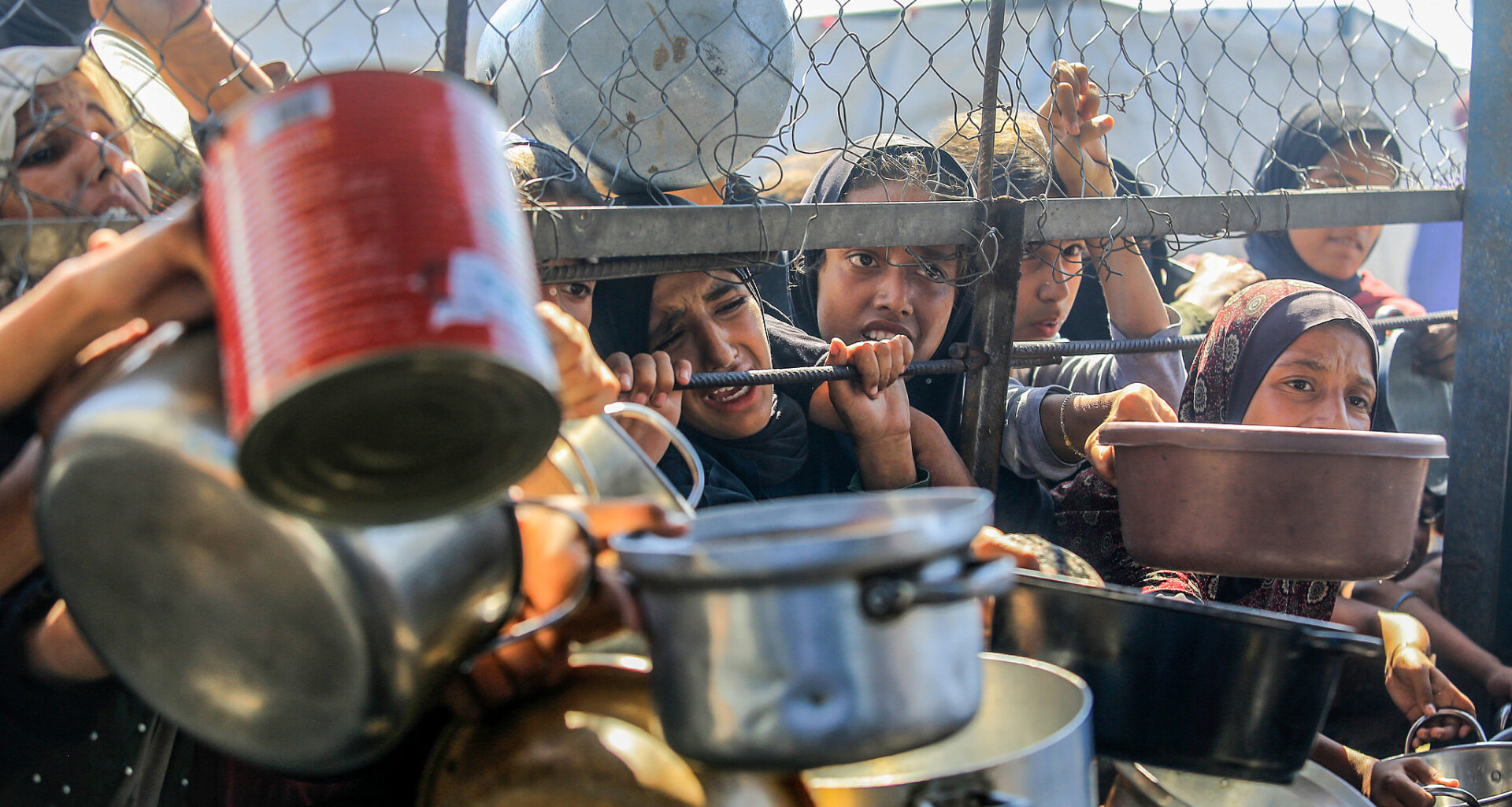 Palestinians try to recive a hot meal prepared by volunteers, in Khan Younis, southern Gaza Strip, June 20, 2025. (Abed Rahim Khatib/Flash90)