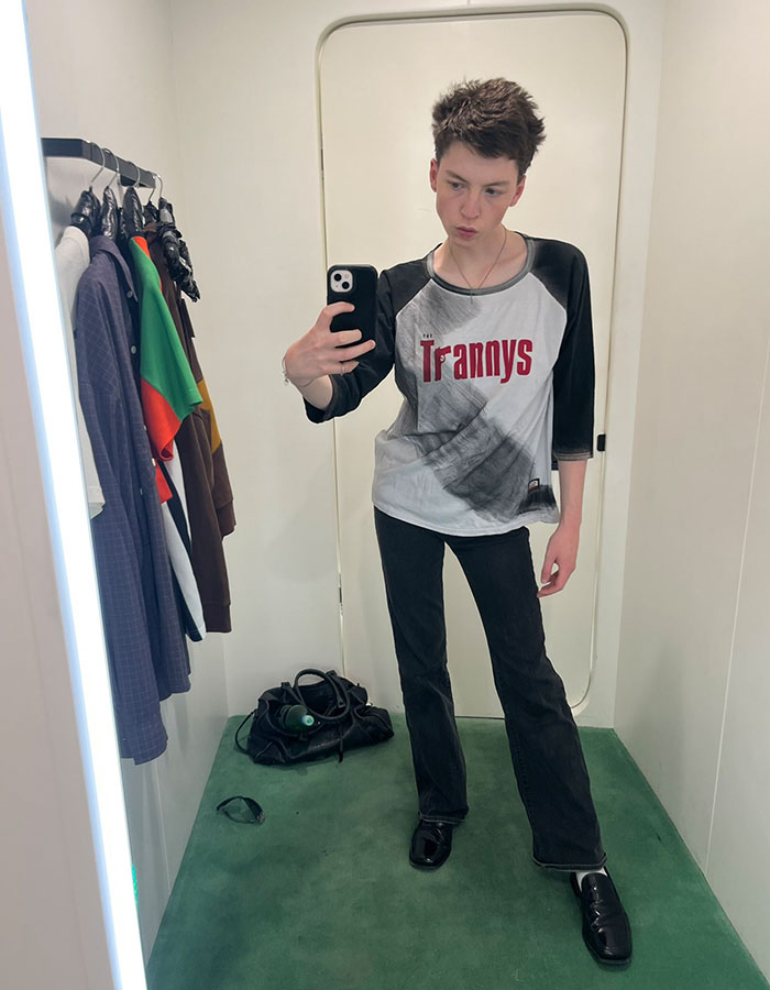 Model taking a mirror selfie in casual clothes, illustrating story of transition and detransition at age 15.