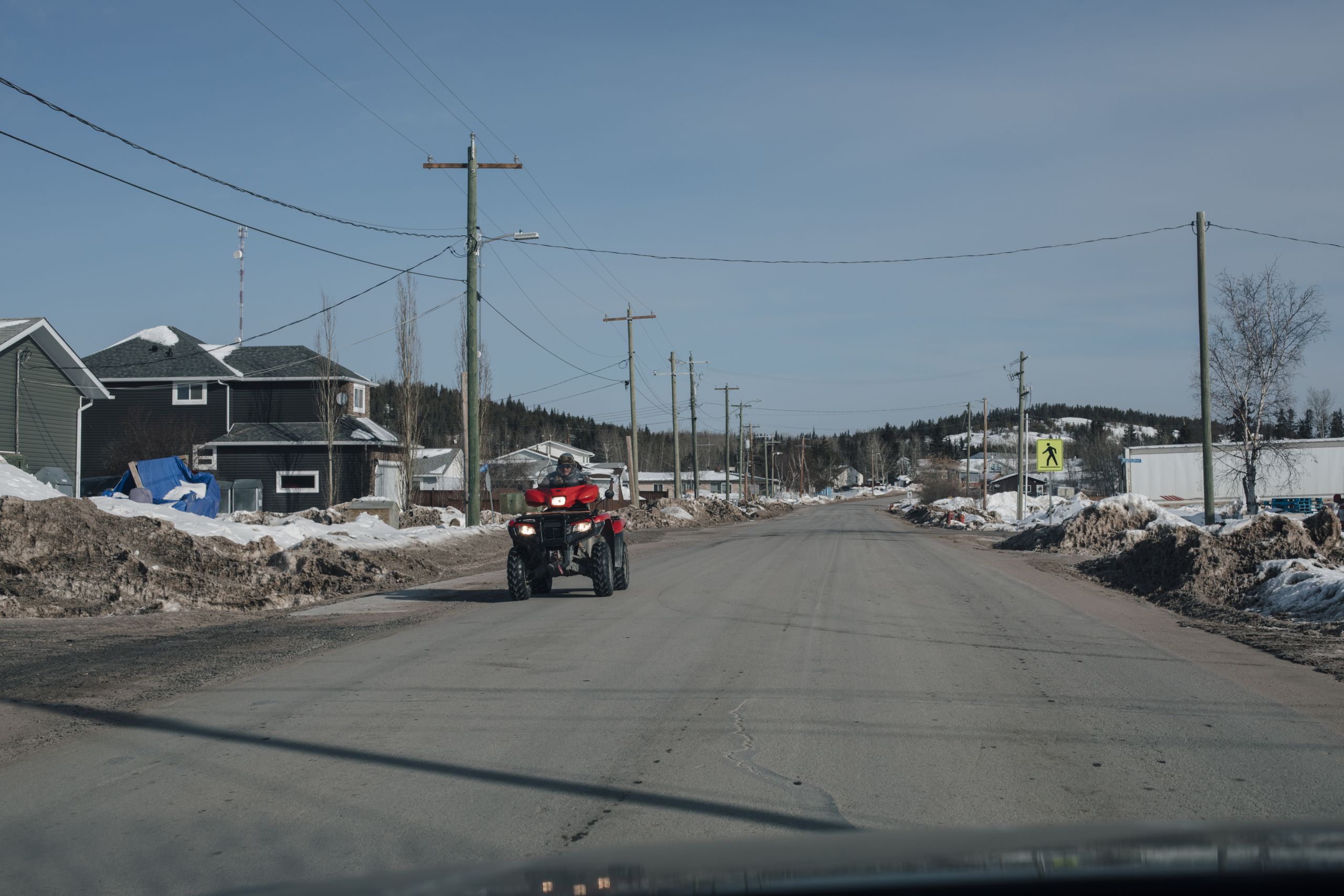 A person drives an ATV down a street in a small town.