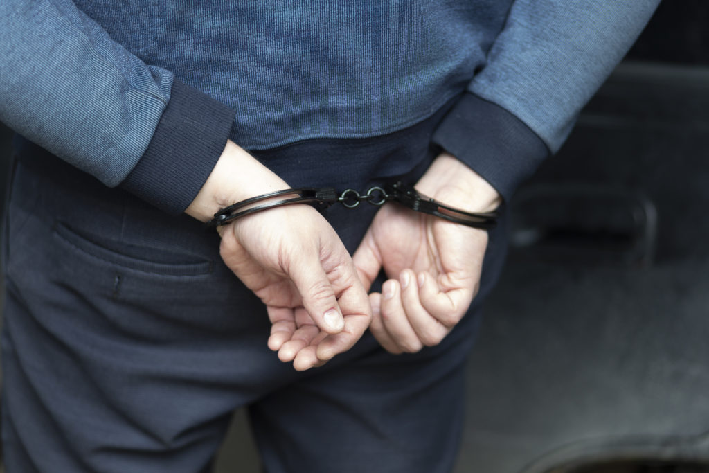 The perpetrator is a man in handcuffs.