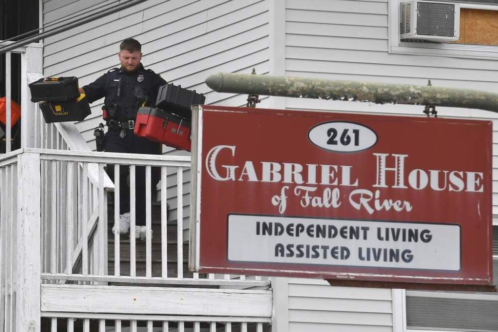 A law enforcement official removes boxes containing patient medications from the Gabriel House assisted living facility following a fire. (Steven Senne/AP)