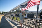 (Left to right) Indivisible Oregon members Jackie Cashion and Keir Karson wave and holler at oncoming cars during rush hour on the Blumenauer Pedestrian Bridge in Portland, Ore., July 17, 2025. These “Good Trouble” demonstrations in various areas around Portland were part of a nationwide effort to protest against the Trump Administration in the name of the late congressman John Lewis of Georgia. 