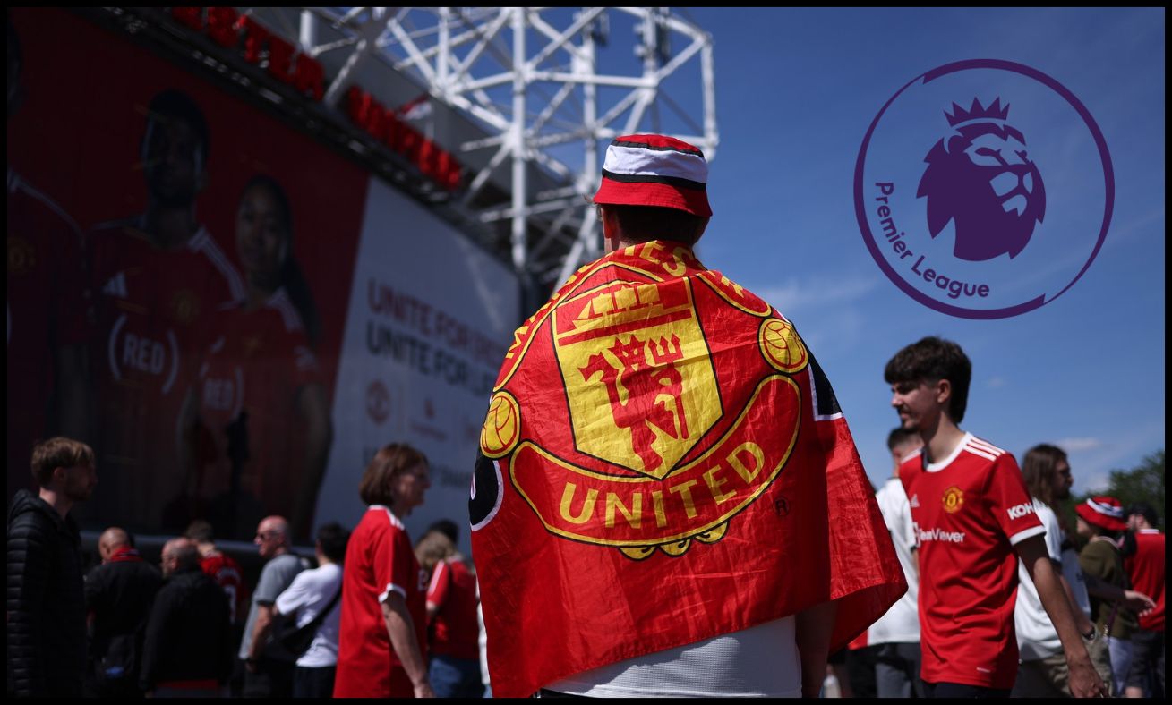 A Manchester United fan stands outside Old Trafford on matchday with a club crest flag draped over his back.