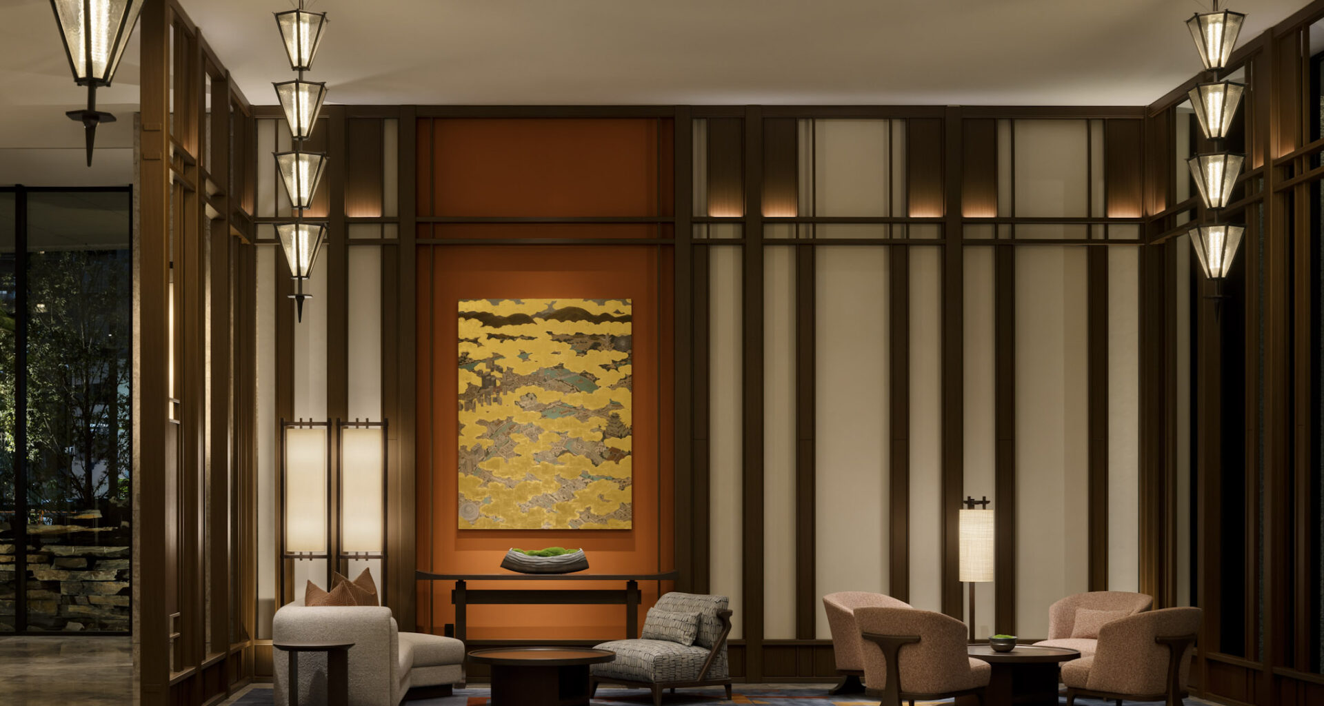 Contemporary hotel lounge with comfortable seating, vertical wood paneling, and a golden-hued abstract painting.