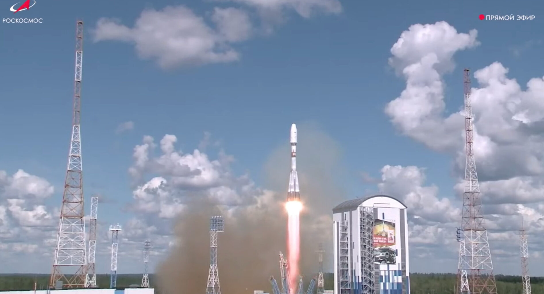 a white rocket launches into a cloud-cluttered blue sky