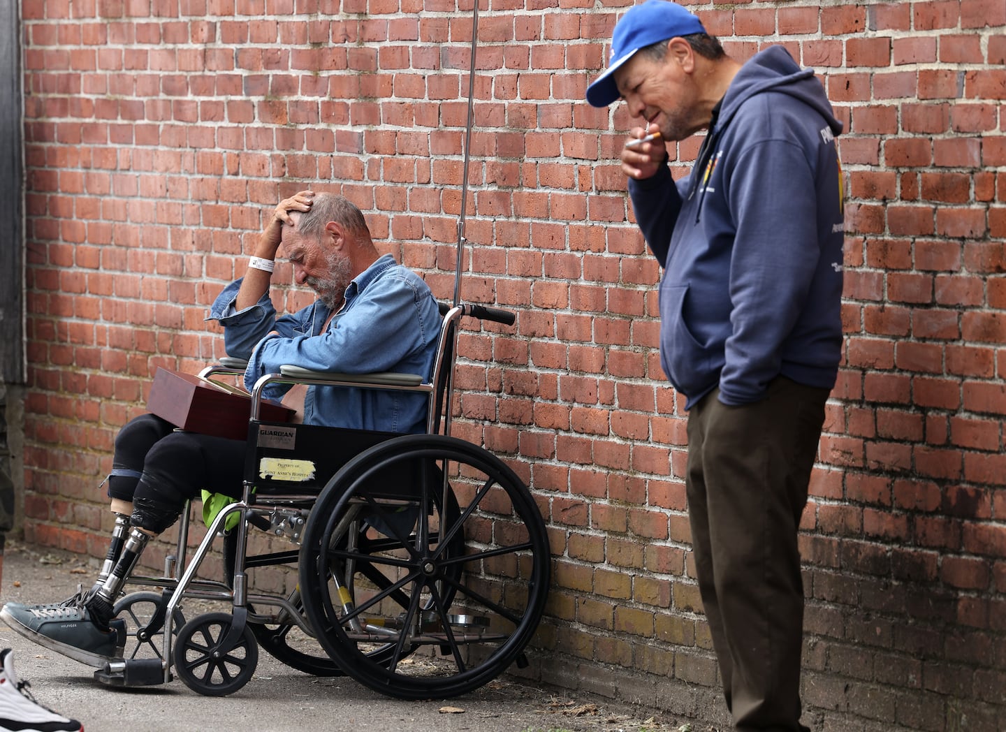  Michael Pimentel, 72, (L) a resident of the Gabriel House Assisted Living Facility where a fire killed 9 people places his hand to his head as he rests outside of the Timao Center where he was evacuated to in Fall River, MA on July 14, 2025. 