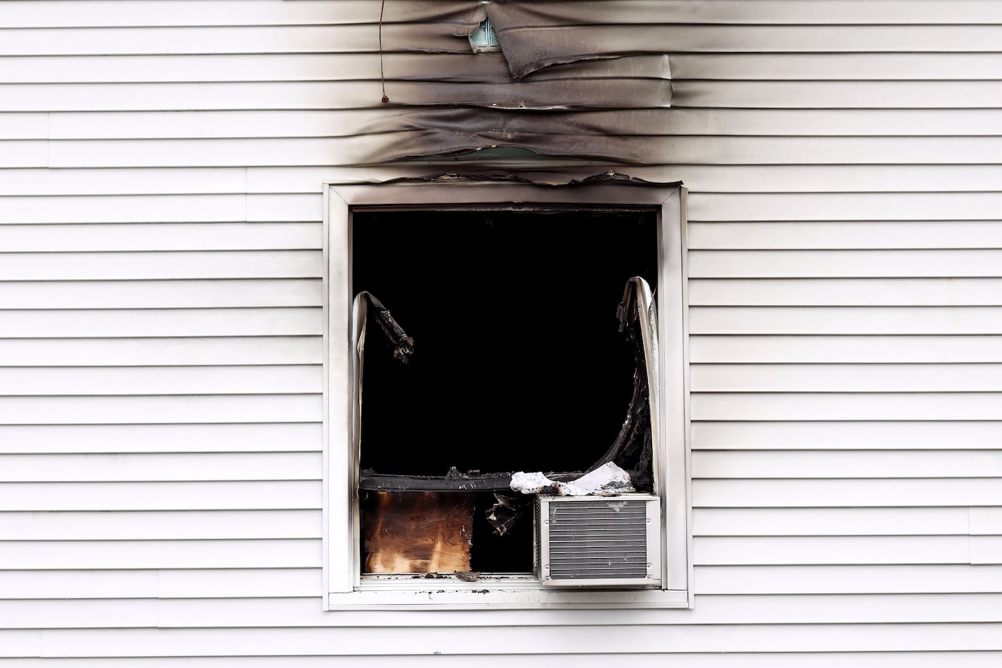 An air conditioner sits in the charred window of the Gabriel House Assisted Living facility on Oliver Street in Fall River Monday morning.