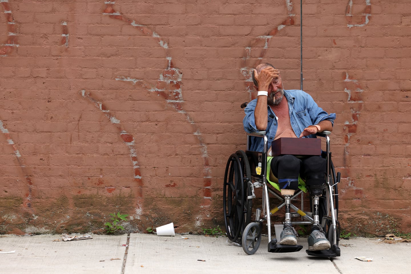 Michael Pimentel, 72, a resident of the Gabriel House Assisted Living Facility where a fire killed 9 people places his hand to his head as he rests outside of the Timao Center where he was evacuated to in Fall River, MA on July 14, 2025.