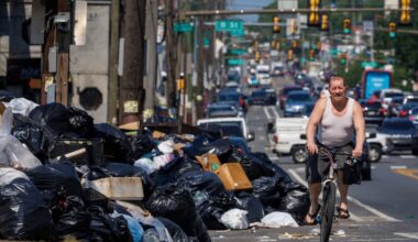 Cyclist riding beside large garbage dump along Allegheny Avenue at C Street during AFSCME District Council 33's strike.