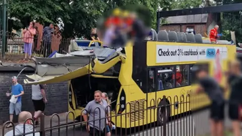 Salar Ardalani A number of people, who have been blurred out, are stood on the top floor of a double decker bus which has had its top sliced off. The back of the bus is handing off and people are watching on from either side of the road. 