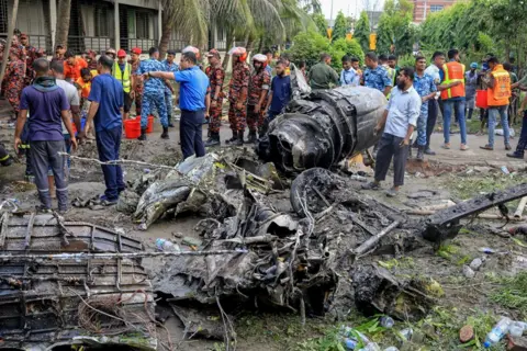 JUBAIR BIN IQBAL/AFP/Getty Images Bangladesh's fire service and security personnel conduct a search and rescue operation after an Air Force training jet crashed into a school in Dhaka on July 21, 2025.  