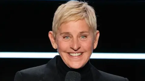 Getty Images Ellen DeGeneres wearing a black jacket, smiling and speaking at the Carol Burnett: 90 Years of Laughter + Love - Season 2023
