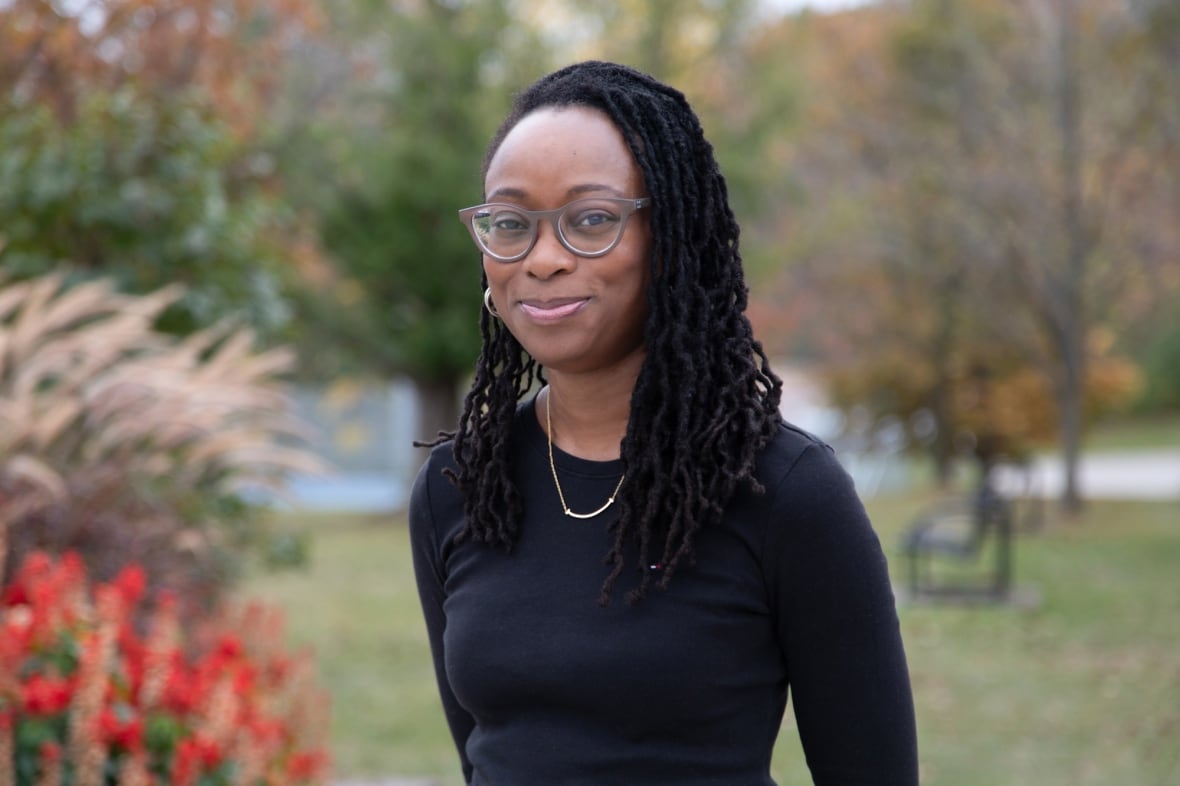 A woman with glasses in a black shirt smiles for the camera