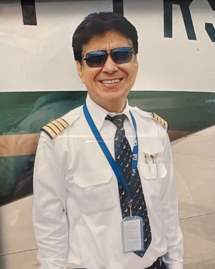Air India pilot smiling in uniform with sunglasses and tie standing near an aircraft on the day of crash.