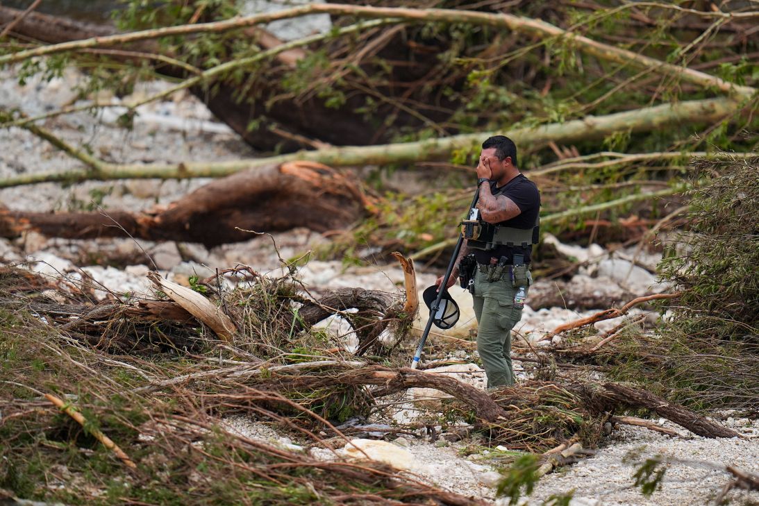 A sheriff's deputy pauses while combing through the banks of the Guadalupe River near Camp Mystic on Saturday in Hunt, Texas.