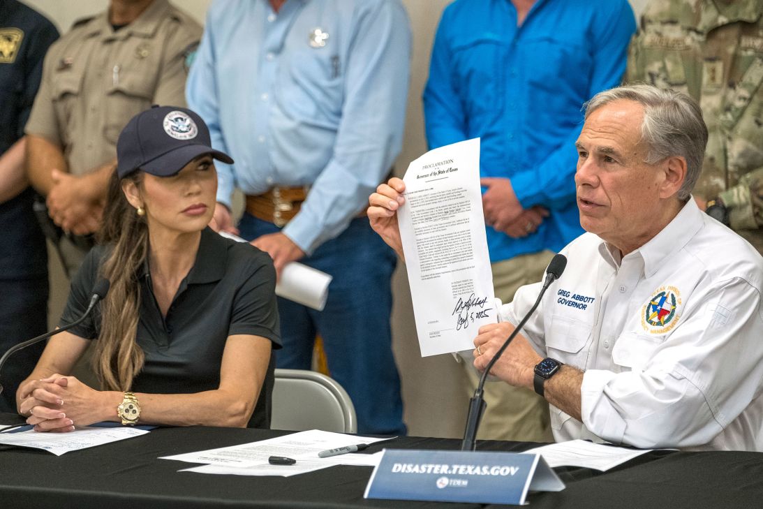 Texas Gov. Greg Abbott signs and holds up an disaster declaration proclamation as Homeland Security Secretary Kristi Noem, left, looks on during a news conference Saturday.